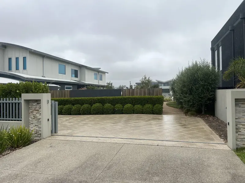 Tidy lawn and coastal planting across the frontage of a holiday home at Safety Beach